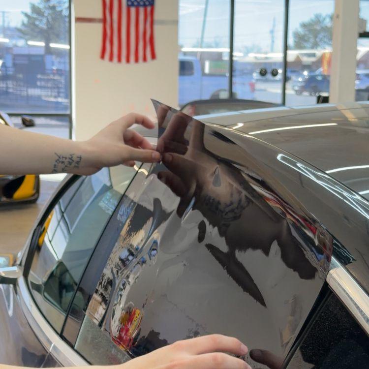 Installer carefully peeling and adjusting tinted film on a car side window
